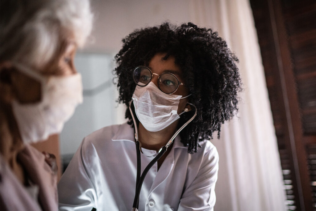 Doctor using stethoscope on a senior patient at home