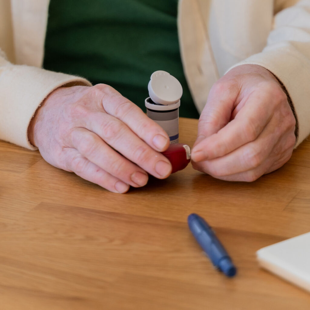Diabetic senior man checking up glucose sugar blood level with electronic device at home kitchen in the morning. health check up. Diabetic Measuring Sugar Levels. senior man with diabetes at home