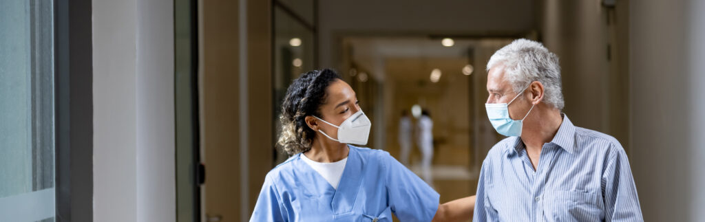 Doctor talking to a patient in the corridor of a hospital while wearing face masks