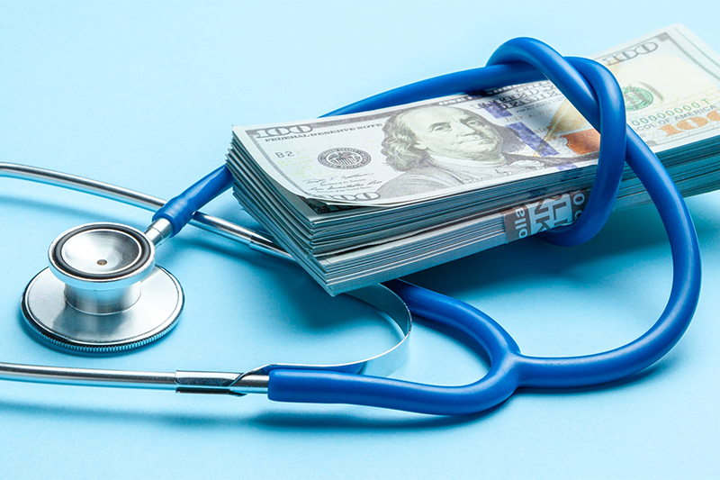 Stack of cash dollars and stethoscope on blue background. The concept of medical strechevka or expensive medicine, doctors salary