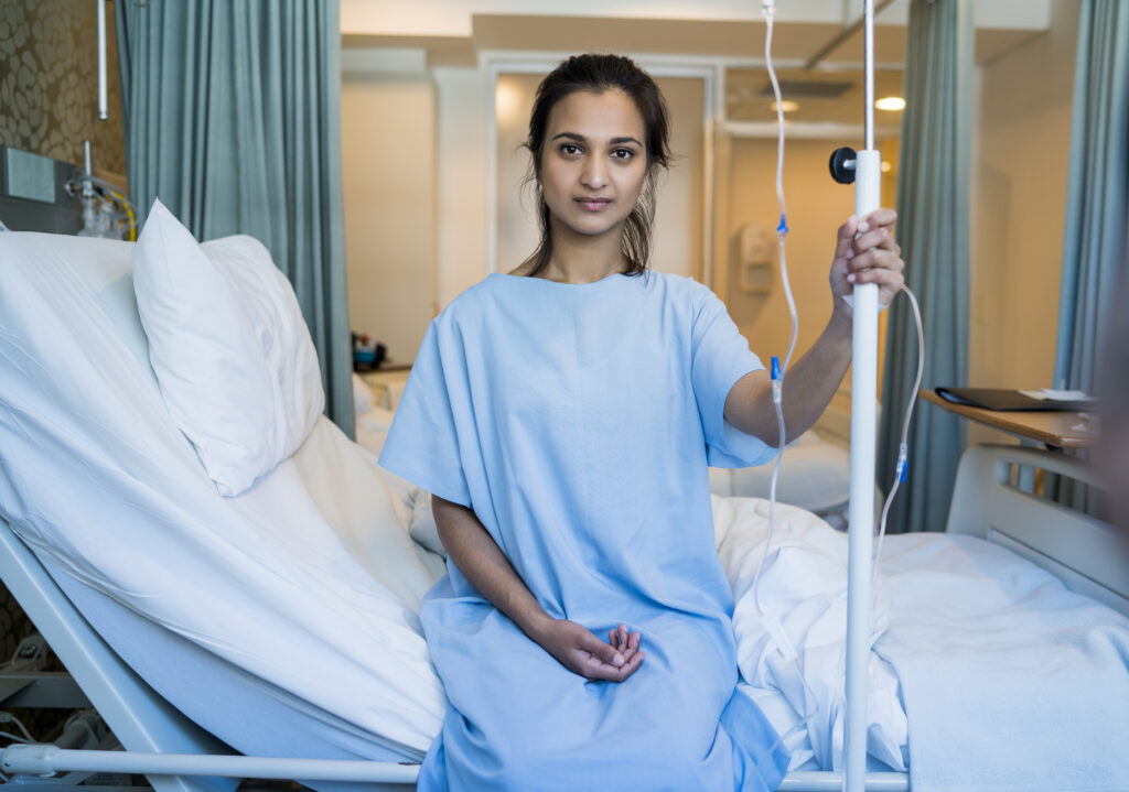 Portrait of young patient holding iv drip in ward