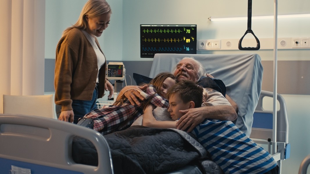 Happy family visiting elderly man in hospital