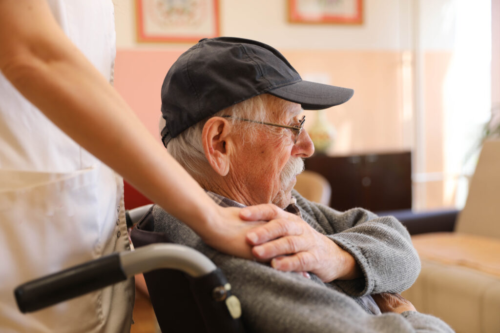 Elderly Man in a Wheelchair Talking to a Nurse at a Nursing Home